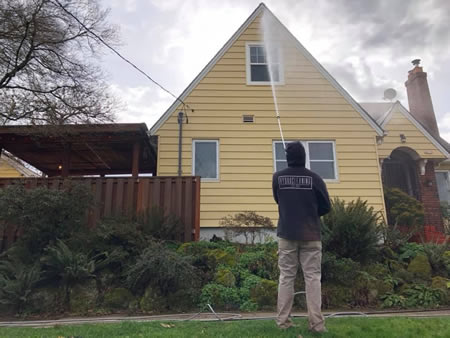 Technician performing soft washing on a craftsman home in portland or
